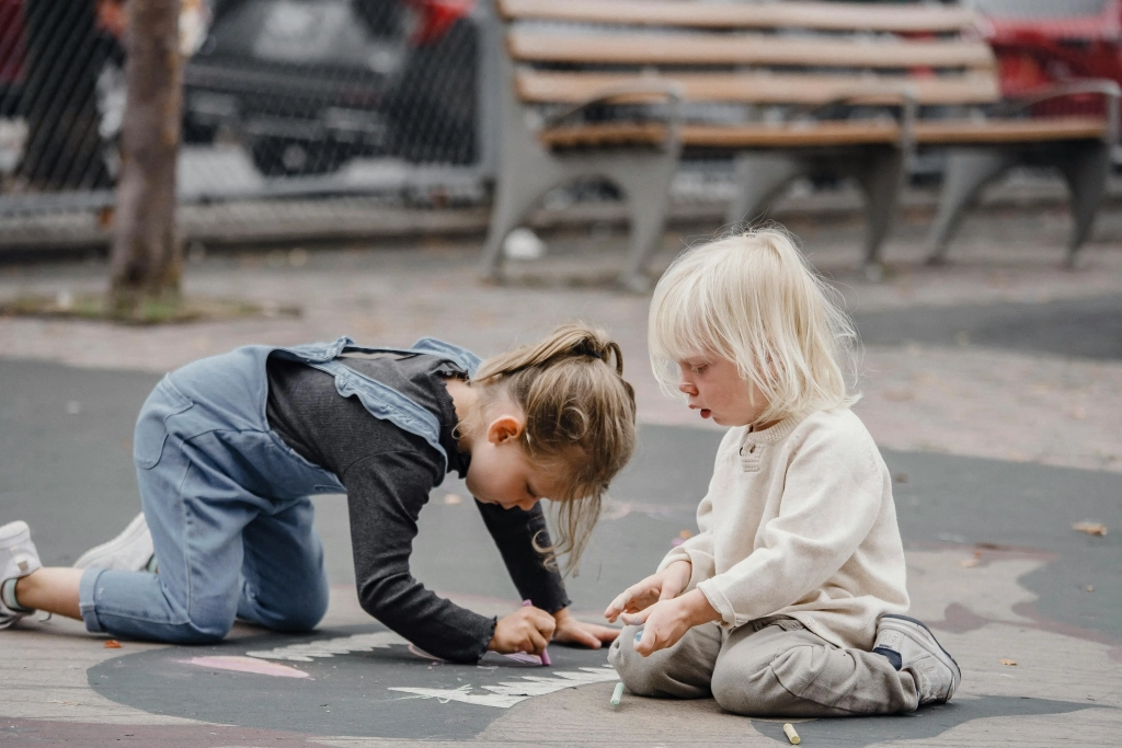 Two young children drawing with chalk outdoords
