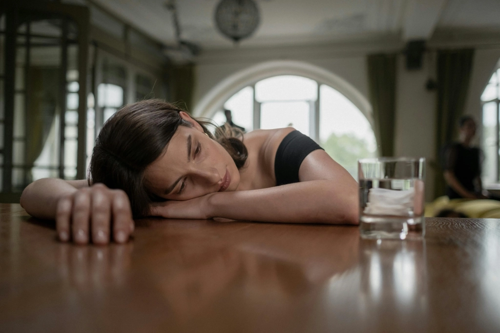 Anxiety woman with head on table and drink next to her